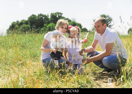 Balades en famille dans le domaine. Famille avec des bulles de savon. Une famille avec deux enfants. Une véritable famille. Banque D'Images