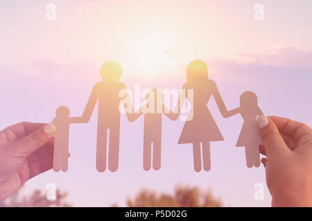 Image du concept de famille heureuse.woman holding paper cut les gens contre le ciel au coucher du soleil Banque D'Images