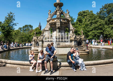 Les personnes bénéficiant de chaud, ensoleillé le arouhnd météo Juin Stewart Memorial Fountain dans parc Kelvingrove dans l'Ouest de la ville Banque D'Images