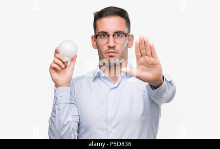 Handsome young man holding lightbulb comme idée avec main ouverte faisant stop avec de sérieux et de confiance, l'expression gestuelle de la défense Banque D'Images