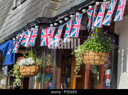 Une rangée de drapeaux Union Jack et deux paniers suspendus à l'extérieur d'une maison publique à Bowness-On-Windermere Banque D'Images
