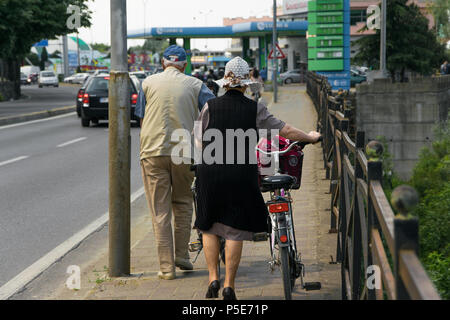 Couple de senior à pied avec des vélos sur le trottoir Banque D'Images