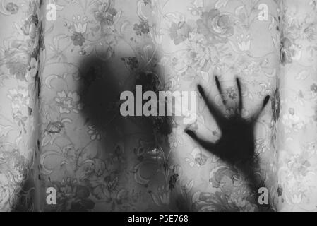 Image en noir et blanc de la mystérieuse ombre derrière un rideau. la peur, mystère, effrayant, glauque et concept paranormal Banque D'Images