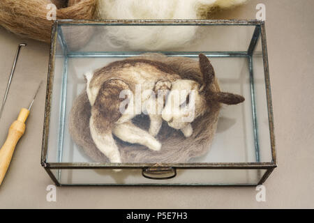 Feutre aiguille lapin sauvage dormir dans une vitrine en verre sur un nid avec des ustensiles de feutrage Banque D'Images