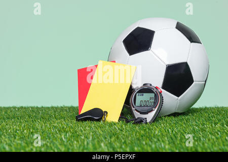 Arbitre de football ou soccer equipmnt et la bille sur l'herbe avec un fond vert. Banque D'Images