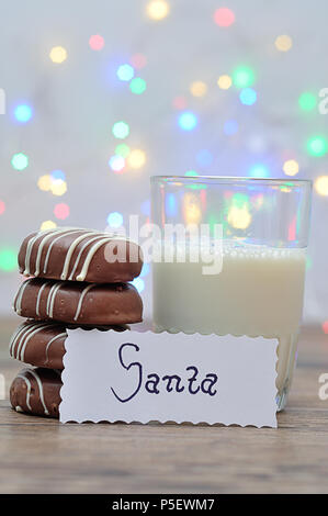 Une pile de biscuits au chocolat et un verre de lait avec une note pour Santa Banque D'Images