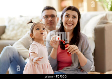 Famille avec des bulles de savon jouant à la maison Banque D'Images