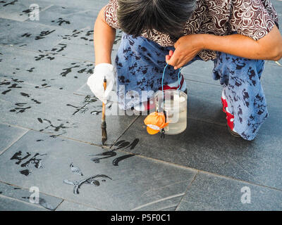 Beijing, Chine - Septembre 2017 : la pratique de la calligraphie de l'eau mais en raison de la chaleur les caractères chinois disparaissent instantanément et ne sont pas lu Banque D'Images