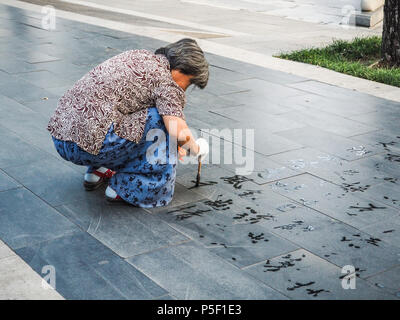 Beijing, Chine - Septembre 2017 : la pratique de la calligraphie de l'eau mais en raison de la chaleur les caractères chinois disparaissent instantanément et ne sont pas lu Banque D'Images