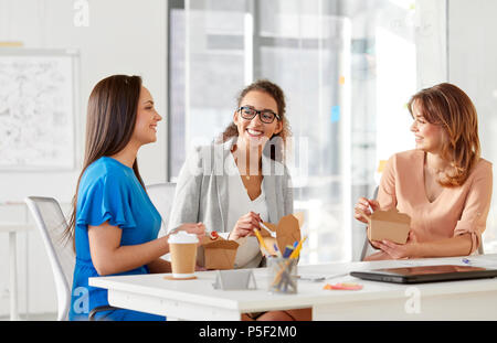 Les femmes d'affaires heureux de manger des aliments à emporter au bureau Banque D'Images