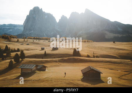 Randonneur à Alpe di Siusi célèbre Langkofel avec des pics de montagne dans l'arrière-plan dans la lumière du matin au lever du soleil d'or, Dolomites, Tyrol du Sud, Italie Banque D'Images