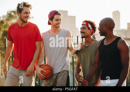 Basket-ball joyeux quatre men walking on parle de la chaussée. Quelques hommes de retour après un match de basket-ball. Banque D'Images