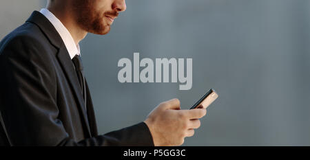 Gros plan d'un homme à l'aide de son téléphone mobile. Homme d'affaires de vêtements formels en regardant son téléphone mobile. Banque D'Images