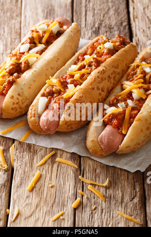 Chili délicieux hot-dogs avec fromage cheddar, hachis de boeuf, l'oignon et la sauce sur la table. vertical, style rustique Banque D'Images