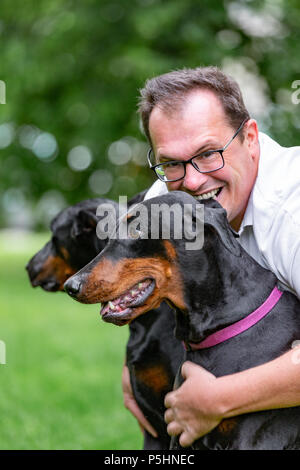 Deux dobermans noirs. Homme marche dans le parc deux Dobermanns pur Banque D'Images