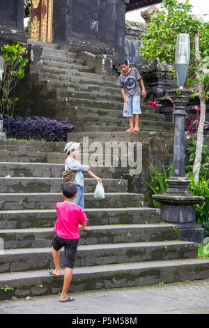 Garçons jouant sur les étapes de le Temple Besakih, perché à 1000m de hauteur sur le sud-ouest de pentes du Mont Agung, Bali (également mère Pura Besakih Temple ou) Banque D'Images