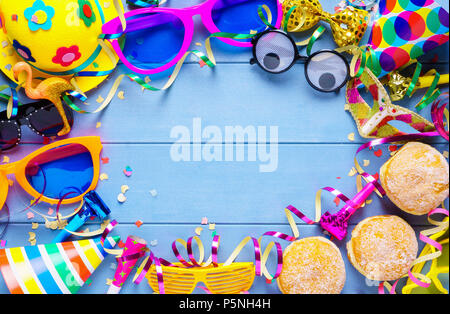 Carnaval haut en couleurs de châssis accessoires, banderoles, party hat et confettis sur planches en bois bleu avec copie espace. Banque D'Images