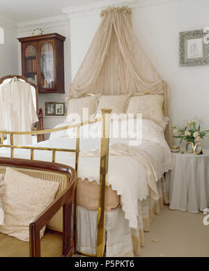 Coronet crème avec rideaux voile au-dessus de lit en laiton avec linge de chambre pays crème Banque D'Images