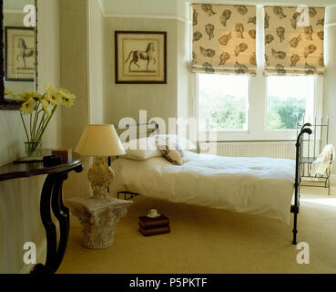 Tête classique stores à motifs en fenêtre sur chambre claire et spacieuse avec moquette crème et en fer forgé et un socle en pierre antique Banque D'Images