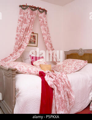 Pays chambre avec coronet avec rose +blanc Toile-de-Jouy rideaux au-dessus vintage grand-lit avec des coussins de toile et jeter Banque D'Images