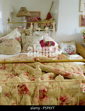 Courtepointe à motifs de roses et de fleurs coussins sur laiton vintage lit simple en chambre cottage Banque D'Images