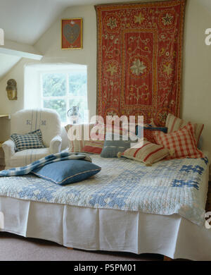 Chambre à coucher style pays indien murale au-dessus de lit à rayures rouge et empilé avec coussins et d'un controle d'arlequin bleu Banque D'Images
