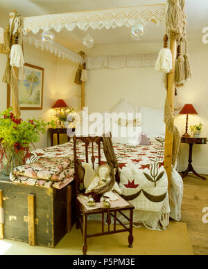 Oreillers blanc et de la dentelle sur woodfour frise rustique lit à baldaquin avec mosaïque de cottage chambre avec coffre en bois ancien Banque D'Images