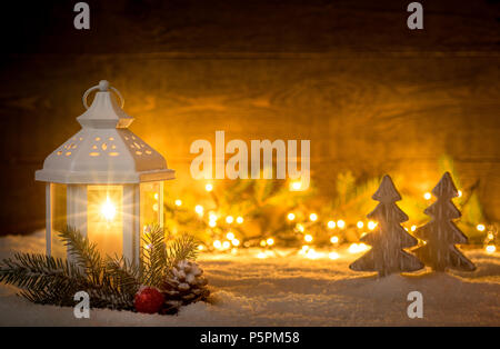 Scène de Noël avec une lanterne, d'arbres, de branches de sapin et de lumières floues devant un conseil en bois foncé que copier l'espace. Banque D'Images