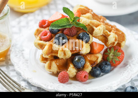 Gaufres maison fraîche avec des framboises, fraises, bleuets et de miel. Délicieux petit déjeuner avec des petits fruits. Selective focus Banque D'Images