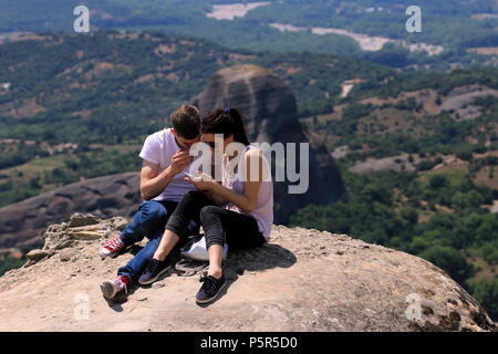 Les jeunes touristes à la recherche d'un smartphone dans des formations rocheuses des météores, près de la ville de Kalambaka, région de Thessalie, Grèce. Banque D'Images