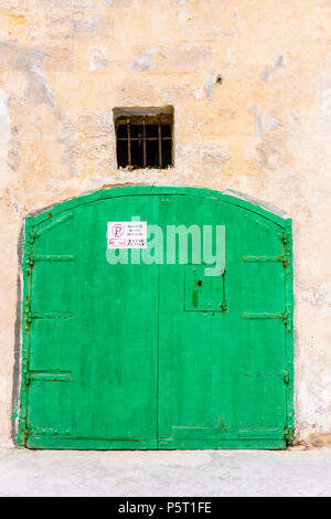 Porte en bois vert sur un garage traditionnel avec un signe de Gozo avise les personnes de ne pas stationner à l'extérieur. Banque D'Images