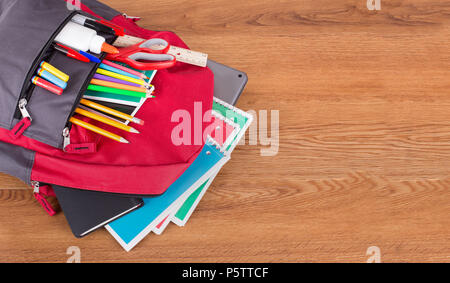 Portrait d'un sac à dos avec un assortiment de fournitures scolaires sur un bureau en bois avec copie espace Banque D'Images