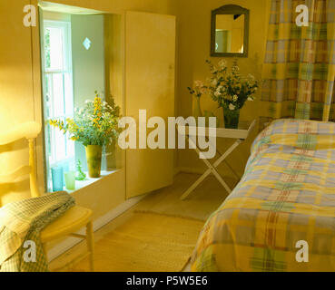 Des volets verts et jaunes sur la porte dans la fenêtre de style cottage économie Chambre avec draps vérifié jaune Banque D'Images