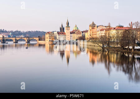 Prague, le Pont Charles et la célèbre horloge près de castle au coucher du soleil. Ses bâtiments reflétant sur l'eau. Nuages sur ciel. Copie négative de l'espace, place de Banque D'Images