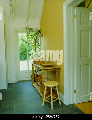 Old pine table console et tabouret en bois en jaune hall avec sol en ardoise Banque D'Images