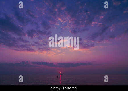 Purple coucher du soleil avec un beau ciel dans les nuages avec un voilier et nageur en eau calme et en mer Baltique Banque D'Images