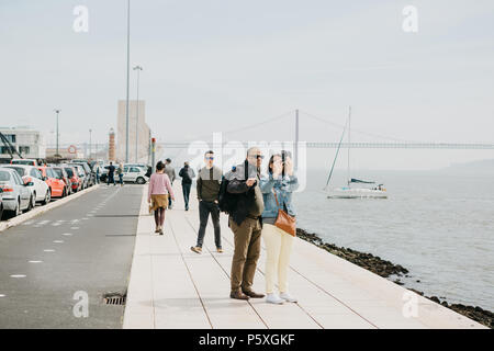 Lisbonne, 1 mai, 2018 : un couple d'hommes et de femmes font un dans le secteur riverain de selfies Belem. Les gens se promènent autour. Dans l'arrière-plan le 25 avril le pont, la mer et le yacht flottent Banque D'Images