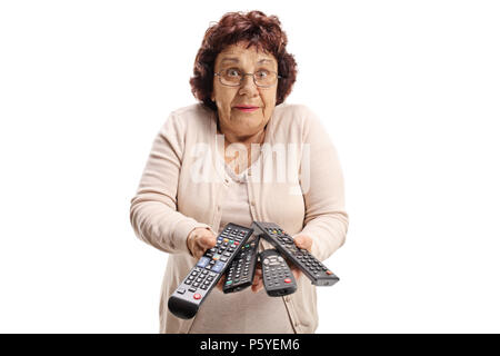 Femme âgée confuse avec les télécommandes isolé sur fond blanc Banque D'Images