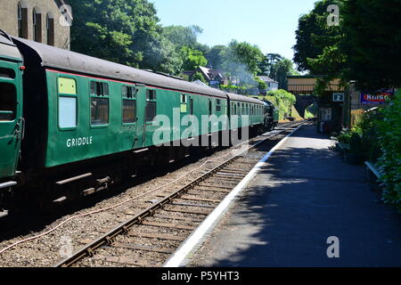 Un train à vapeur tirant les entraîneurs attendent d'écarter d'une station. Banque D'Images