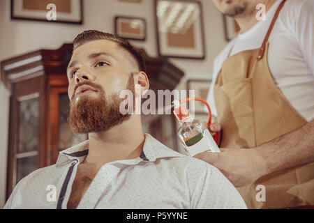 Homme avec barbe utilise les services d'un salon de coiffure. Photo en style vintage Banque D'Images
