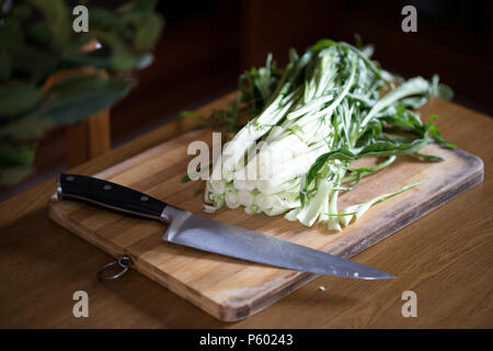 Chicorée catalogne ou puntarelle en italien, sur planche de bois avec un couteau. Ce type de la chicorée est un légume traditionnel utilisé dans la cuisine romaine. Banque D'Images