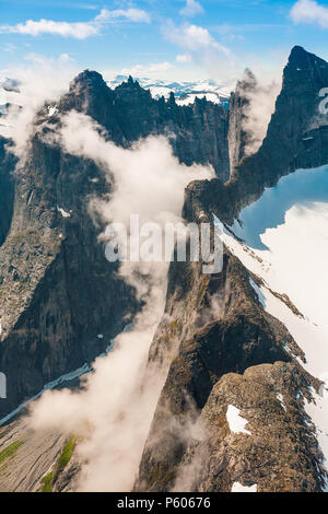 Vue aérienne des montagnes dans la vallée de Romsdalen, Møre og Romsdal (Norvège). Les 3000 pieds sur le plan vertical mur Troll est partiellement couvert par le brouillard. Banque D'Images