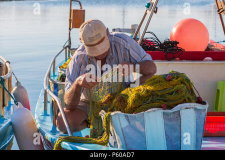 Les pêcheurs de la réparation des filets de pêche sur un bateau de pêche, au style traditionnel local attaché dans le vieux port, Ayia Napa, Chypre Banque D'Images