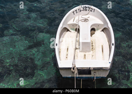 Petit bateau à rames en fibre de verre attaché dans un port peu profond. Banque D'Images