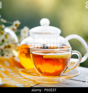 Tasse avec du thé chaud à la menthe et le thym une sur une table en bois dans un jardin d'été. Banque D'Images