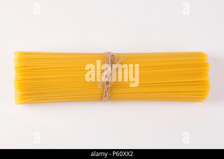 Spaghetti italien attachées avec un fil marron. Pâte de matières premières sur un arrière-plan vide Banque D'Images