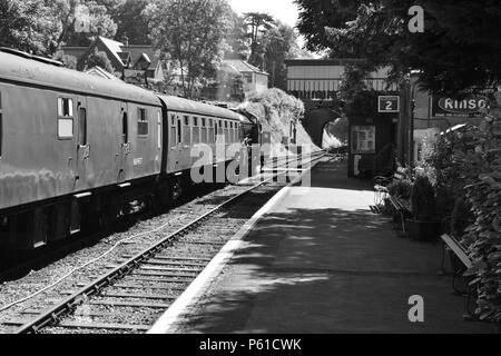 Un train à vapeur tirant les entraîneurs attendent d'écarter d'une station. Banque D'Images