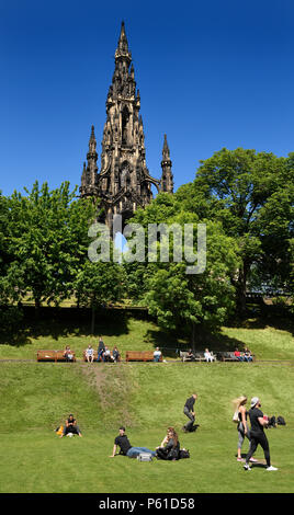 Les gens et les touristes dans les jardins de Princes Street park sous le Scott Monument à Edinburgh Scotland UK avec ciel bleu Banque D'Images