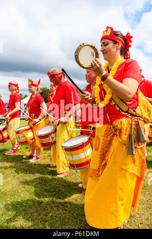 Fogo Bloco Sambra Drumming Bande, à Custard Pie Championship, Coxhealth. Vêtus de rouge et jaune, le long de la ligne de tambours et joueur de tambourin. Banque D'Images