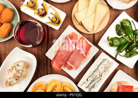 La nourriture de l'Espagne. Un passage photo gros plan de divers tapas espagnoles, tourné à partir de ci-dessus sur une texture rustique foncé. Jambon, fromage, vin, Anneaux de calamars, Banque D'Images